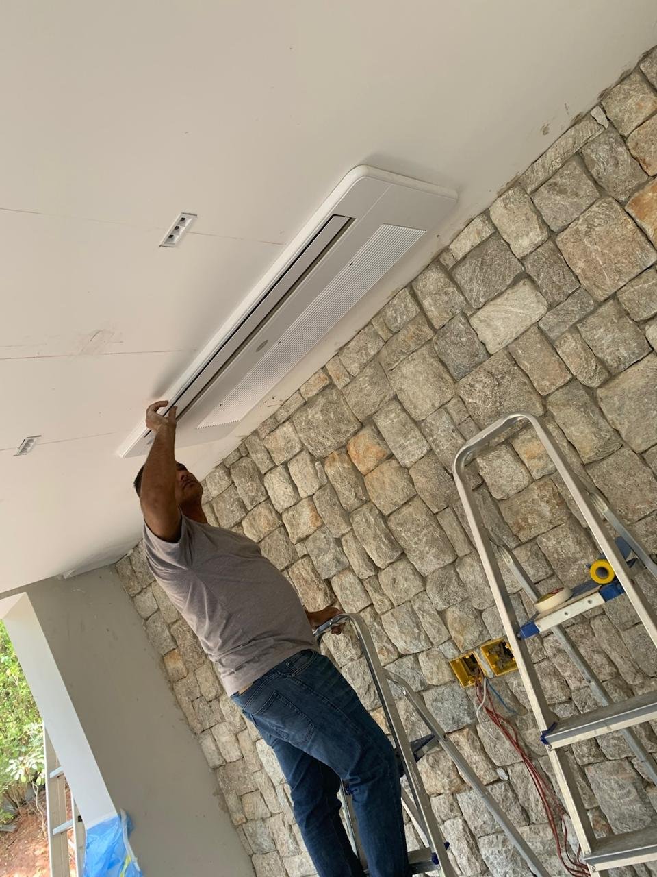 Técnico da AFL instalando ar-condicionado cassete no teto